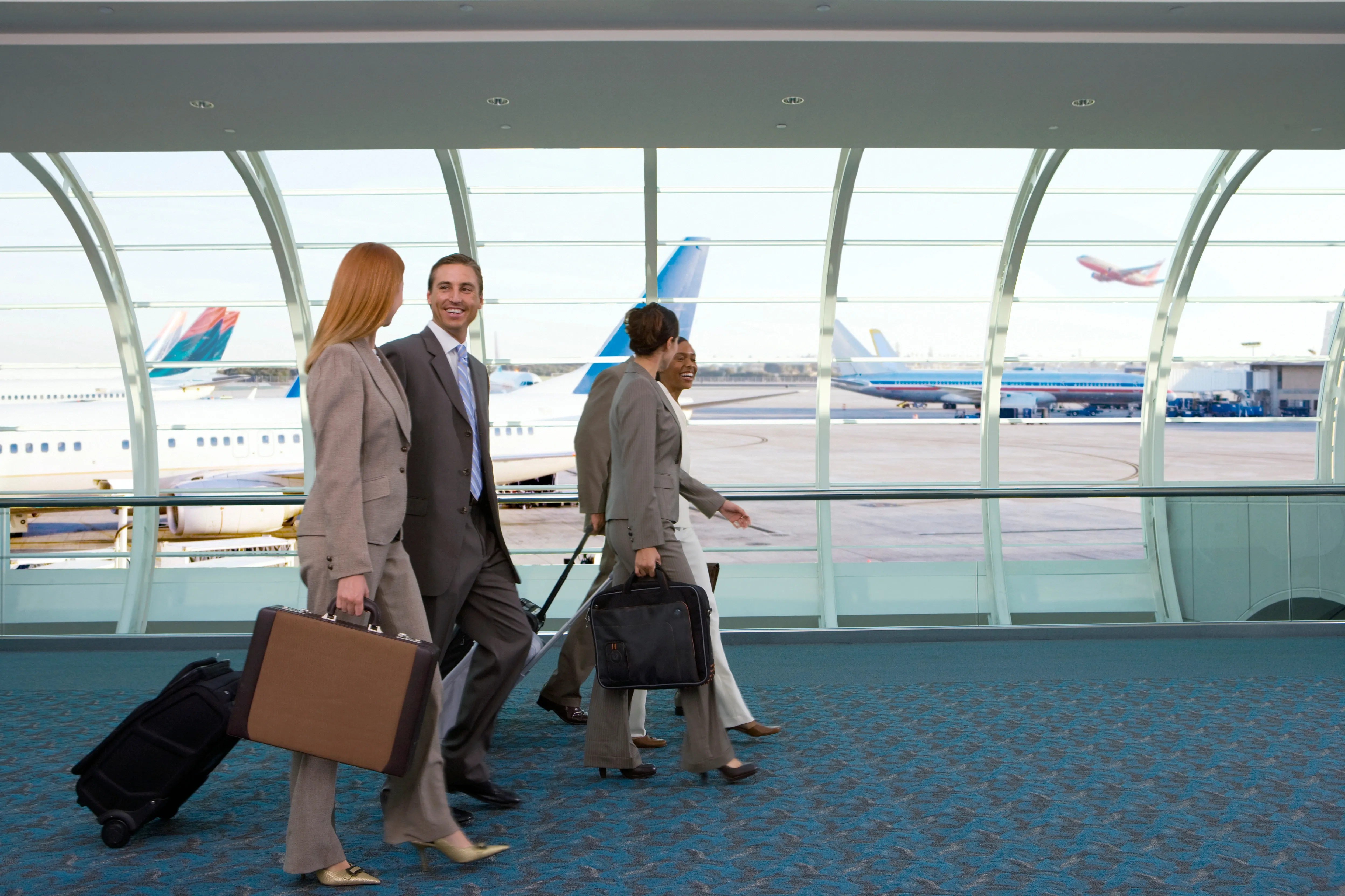 Business travelers walking at burbank airport with luggage.